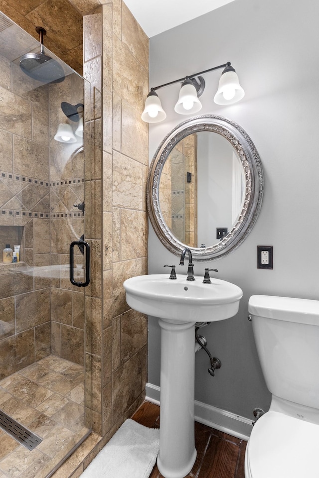 bathroom with toilet, hardwood / wood-style floors, and a shower with shower door