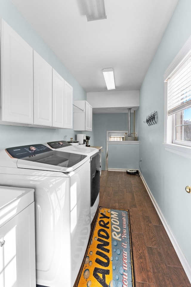 clothes washing area with cabinets, washing machine and dryer, and dark hardwood / wood-style floors