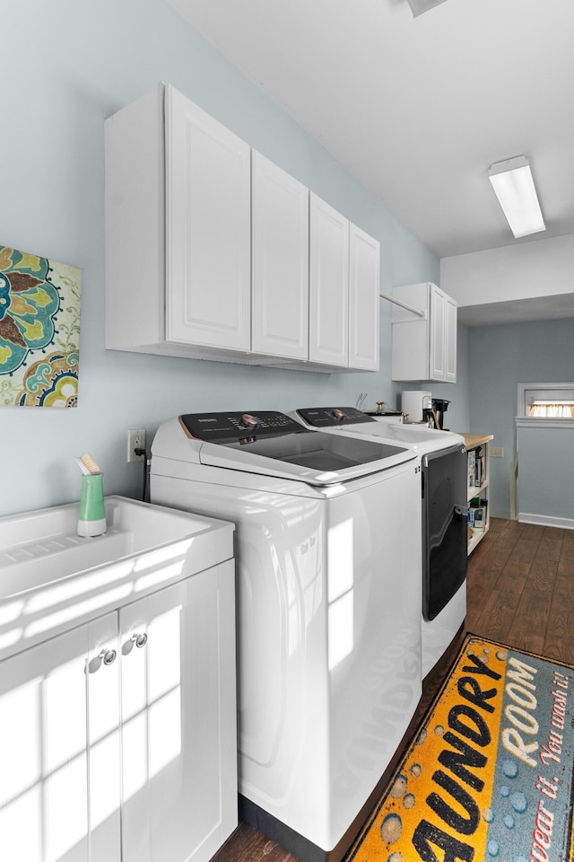 laundry area featuring cabinets, dark hardwood / wood-style floors, and washing machine and clothes dryer