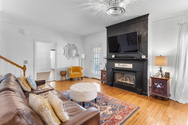 living room with hardwood / wood-style flooring, ornamental molding, and a fireplace