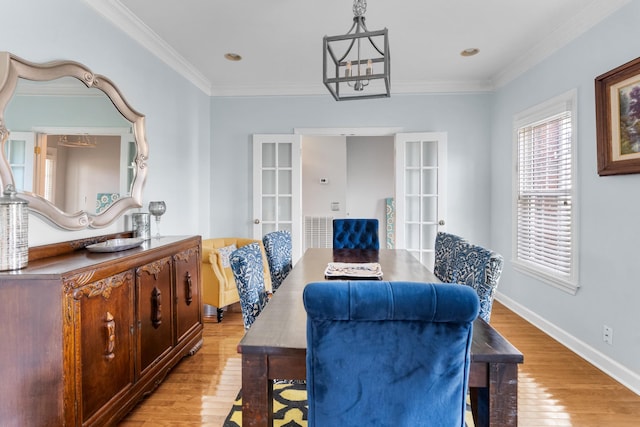 dining space featuring crown molding, light hardwood / wood-style floors, french doors, and a chandelier