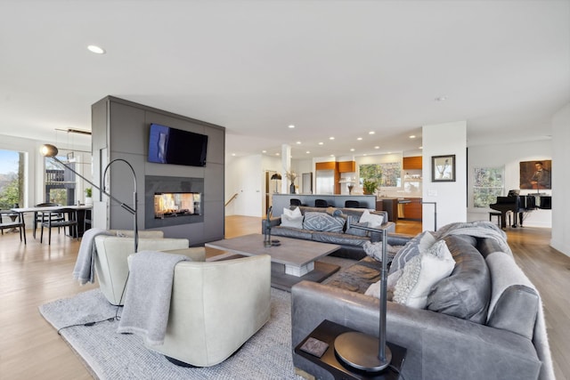 living room featuring light wood-type flooring and a large fireplace