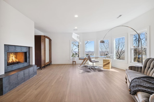 interior space with light wood-type flooring and a tile fireplace