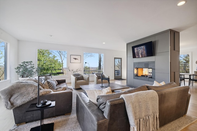 living room with a tile fireplace and light wood-type flooring