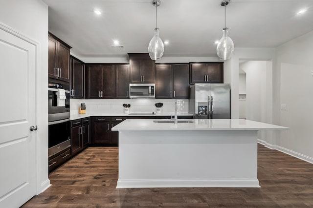 kitchen featuring sink, stainless steel appliances, dark hardwood / wood-style floors, pendant lighting, and a kitchen island with sink