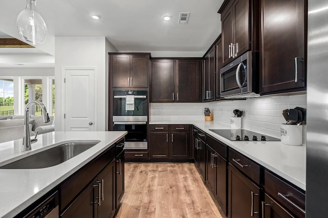 kitchen with sink, decorative backsplash, decorative light fixtures, light hardwood / wood-style floors, and stainless steel appliances