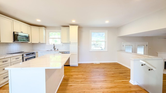 kitchen featuring a wealth of natural light, a kitchen island, light wood-type flooring, and appliances with stainless steel finishes