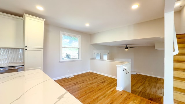 kitchen with white cabinetry, tasteful backsplash, light stone counters, light hardwood / wood-style flooring, and stainless steel dishwasher