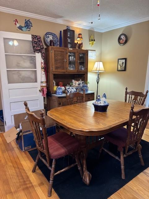 dining room with crown molding, light hardwood / wood-style flooring, and a textured ceiling