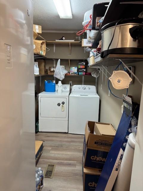 laundry area with washer and dryer, a textured ceiling, and light wood-type flooring