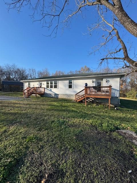 back of property featuring a wooden deck and a yard