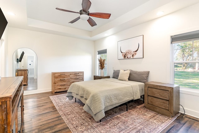 bedroom featuring dark hardwood / wood-style floors, a raised ceiling, and ceiling fan