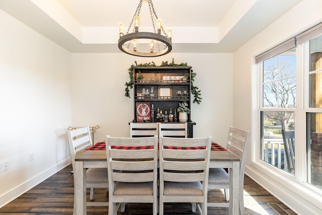 dining room featuring a chandelier, dark hardwood / wood-style floors, and a raised ceiling