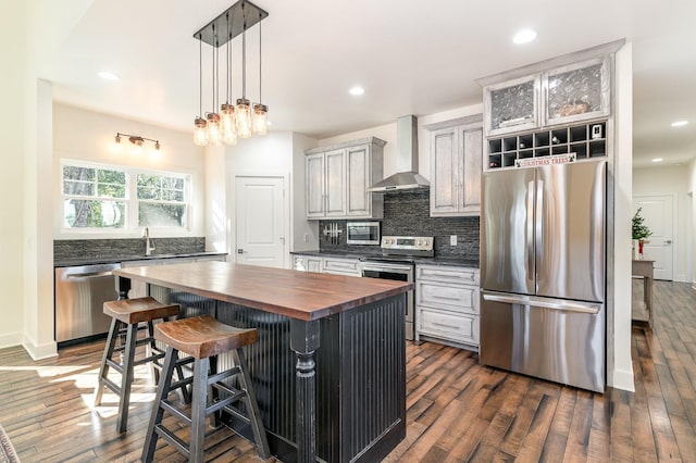 kitchen with butcher block counters, wall chimney exhaust hood, stainless steel appliances, and dark hardwood / wood-style floors