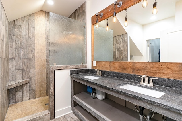 bathroom with tiled shower, hardwood / wood-style floors, vanity, and vaulted ceiling