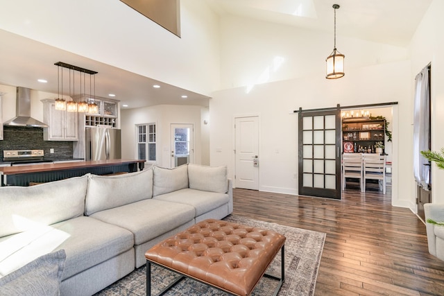 living room with dark hardwood / wood-style floors, a barn door, and high vaulted ceiling