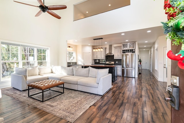 living room featuring dark hardwood / wood-style floors, ceiling fan, and a high ceiling