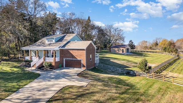 view of front facade with a porch, a garage, a rural view, and a front lawn