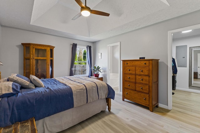 bedroom with ceiling fan, light hardwood / wood-style floors, a textured ceiling, and ensuite bath