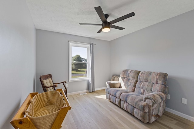 sitting room featuring ceiling fan, light hardwood / wood-style floors, and a textured ceiling