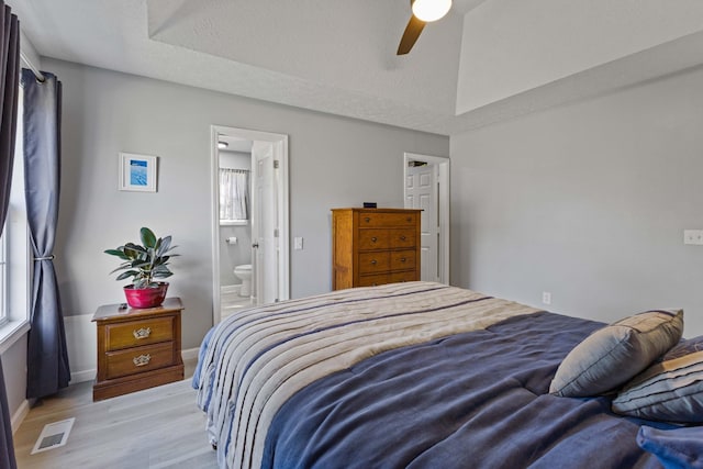 bedroom with ensuite bathroom, light hardwood / wood-style flooring, ceiling fan, and a textured ceiling