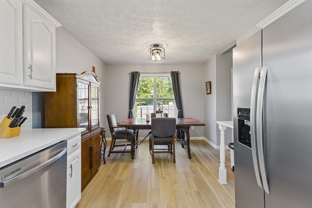 kitchen featuring white cabinets, decorative backsplash, stainless steel appliances, and light hardwood / wood-style floors