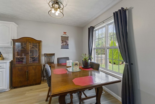 dining area with a textured ceiling and light hardwood / wood-style flooring