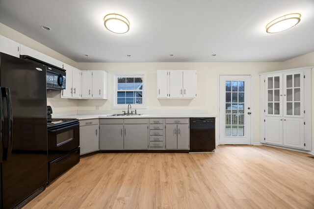 kitchen with white cabinetry, black appliances, and light wood-type flooring