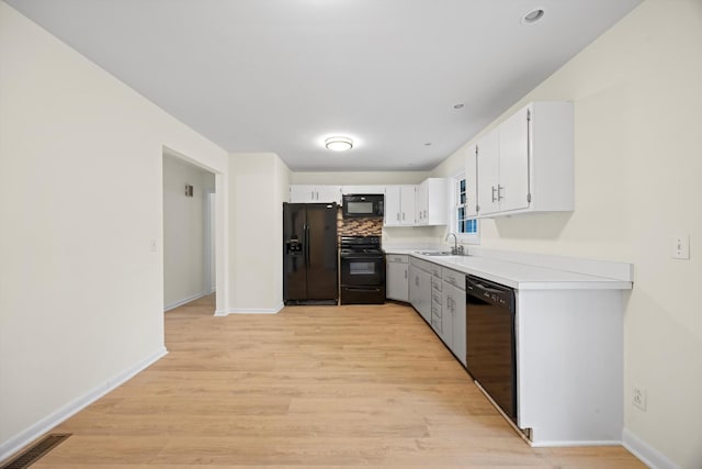 kitchen featuring sink, light hardwood / wood-style flooring, decorative backsplash, white cabinets, and black appliances