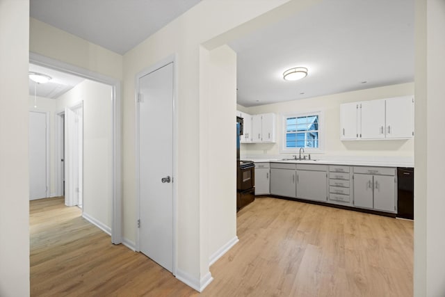 kitchen with sink, white cabinets, black appliances, and light hardwood / wood-style flooring