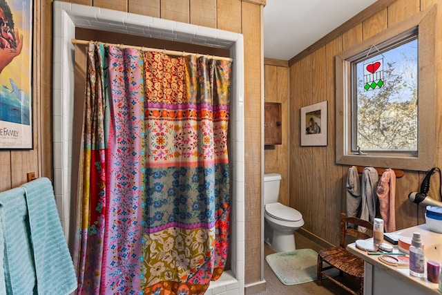 bathroom featuring a shower with shower curtain, vanity, toilet, and wood walls