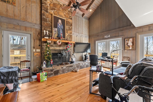 living room featuring light hardwood / wood-style flooring, high vaulted ceiling, plenty of natural light, and wood walls