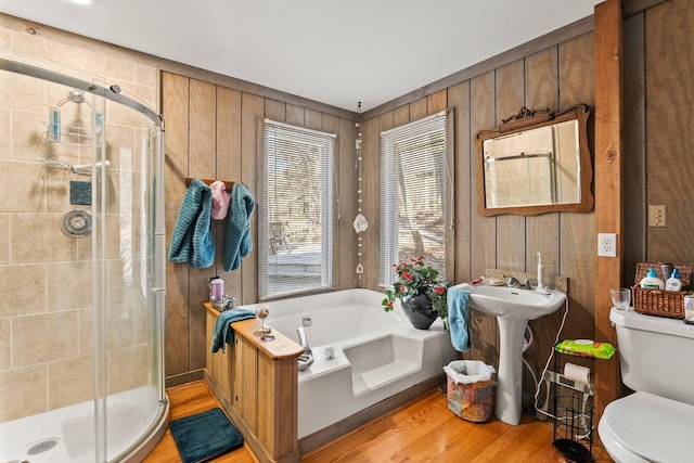 bathroom with toilet, wood walls, hardwood / wood-style floors, and shower with separate bathtub