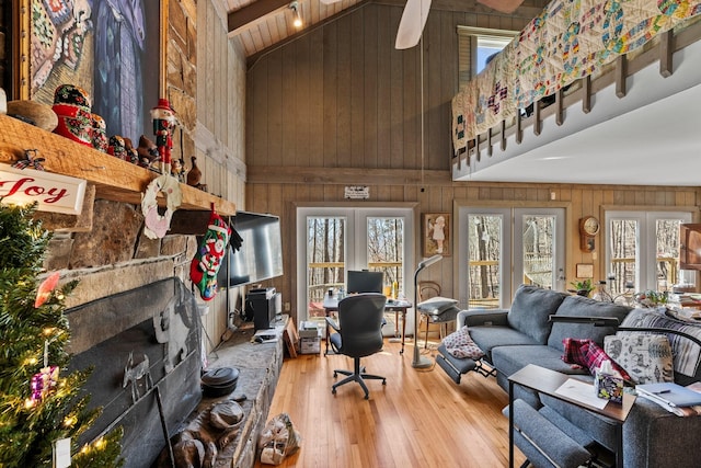 living room featuring hardwood / wood-style floors, high vaulted ceiling, ceiling fan, and wooden walls