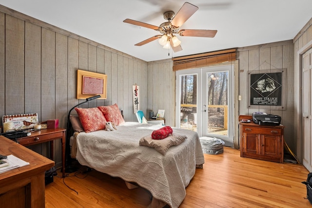 bedroom featuring ceiling fan, wooden walls, and light wood-type flooring