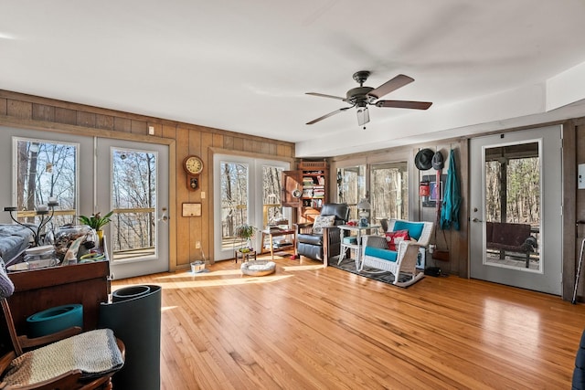 living area featuring ceiling fan, wood walls, and light hardwood / wood-style flooring