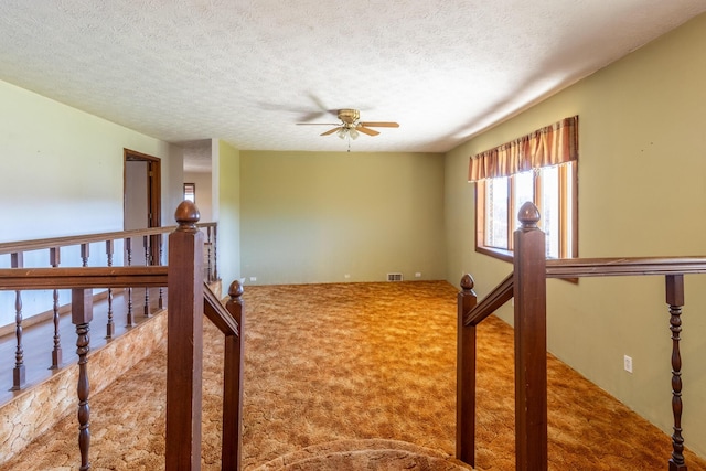 spare room with ceiling fan, carpet, and a textured ceiling