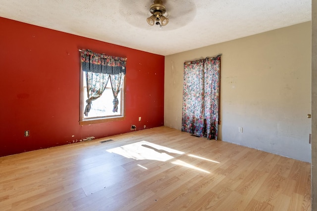 spare room with a textured ceiling, light hardwood / wood-style flooring, and ceiling fan