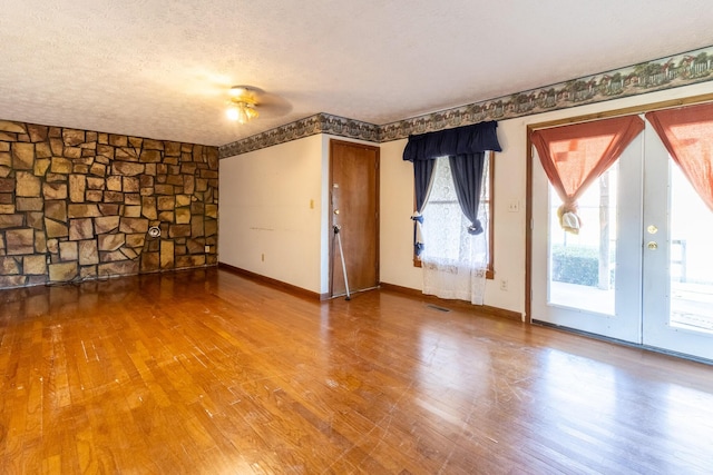 empty room with a textured ceiling, hardwood / wood-style flooring, and ceiling fan