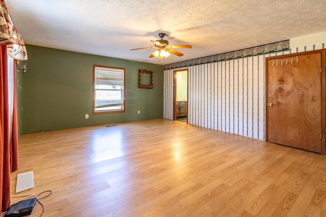 unfurnished room featuring a textured ceiling, light wood-type flooring, and ceiling fan