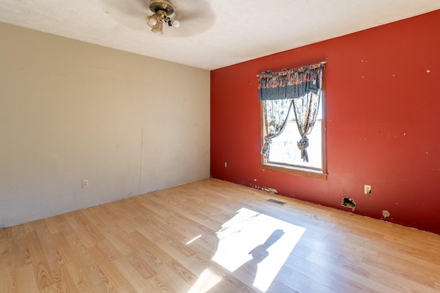 empty room with ceiling fan and light hardwood / wood-style flooring