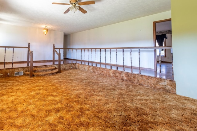 empty room featuring carpet flooring, a textured ceiling, and ceiling fan