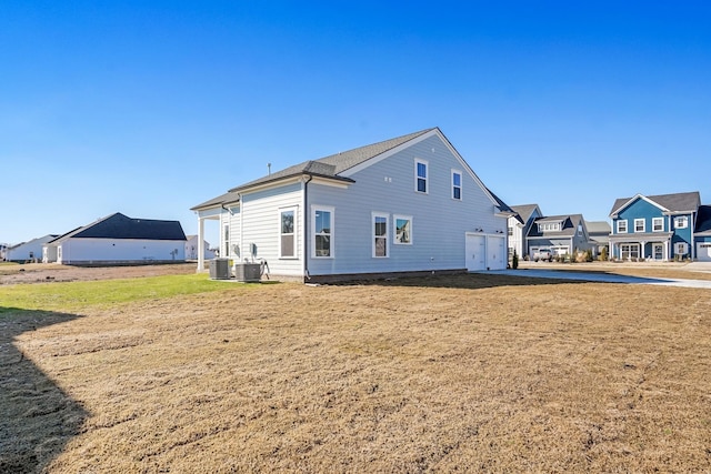 rear view of house with a lawn, central AC unit, and a garage