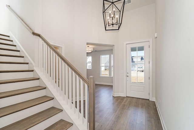 entryway with wood-type flooring, a notable chandelier, and a high ceiling