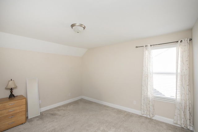 spare room with a wealth of natural light, light colored carpet, and vaulted ceiling