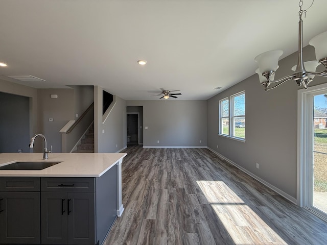 kitchen featuring ceiling fan with notable chandelier, gray cabinets, dark hardwood / wood-style flooring, and sink