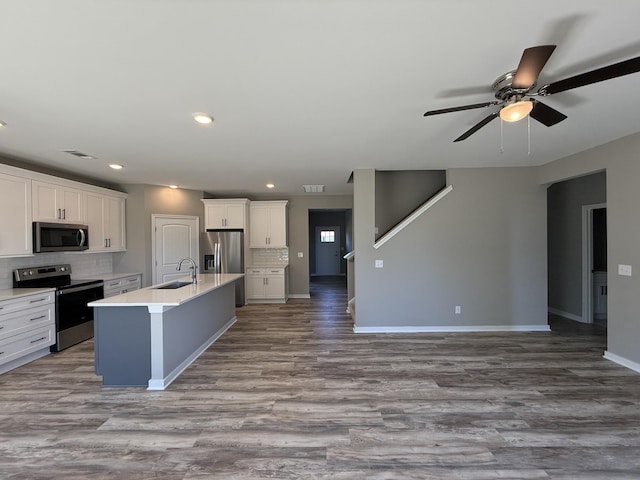 kitchen with stainless steel appliances, white cabinetry, a kitchen island with sink, and sink