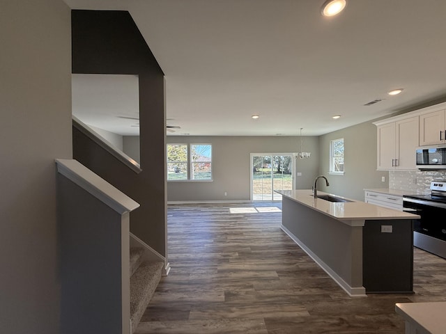 kitchen featuring white cabinetry, sink, dark hardwood / wood-style floors, a center island with sink, and appliances with stainless steel finishes