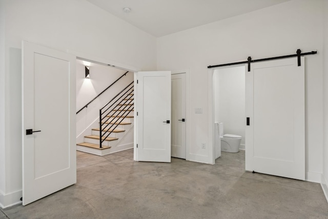 unfurnished bedroom featuring a barn door and ensuite bath