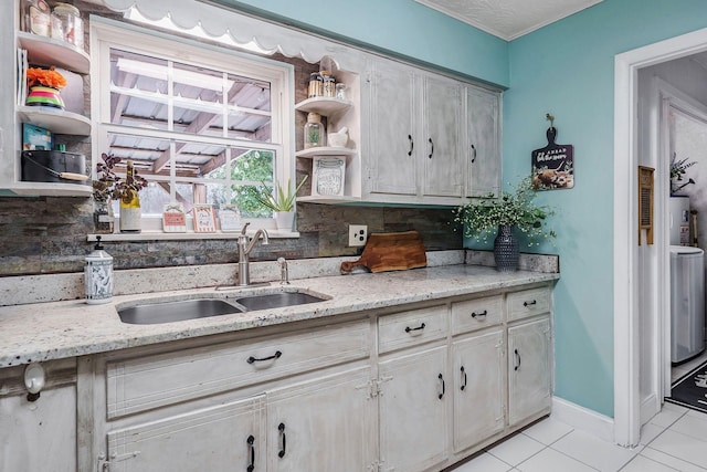 kitchen with tasteful backsplash, light stone counters, water heater, sink, and light tile patterned floors